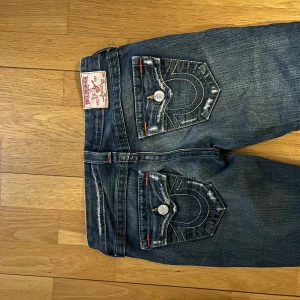 Blå jeans med broderade bakfickor - Snygga blå jeans från True Religion med broderade detaljer på bakfickorna. De har coola slitningar och är storlek W25🩷Köptes för 2000kr ,inte mycket använda alls🩷tyvärr för små för mig🩷PRISET KAN DISKUTERAS