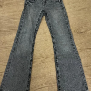 Grå jeansbyxor - Snygga grå jeansbyxor med bootcut-stil. De har en klassisk femficksdesign och knappar på bakfickorna. Perfekta för en avslappnad look.