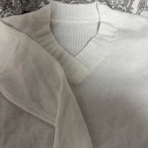 Vit stickad tröja med v-ringning - Säljer en stilren vit stickad tröja med v-ringning. Perfekt för kyligare dagar med sin mjuka och bekväma passform. Ett måste i garderoben för en klassisk look.