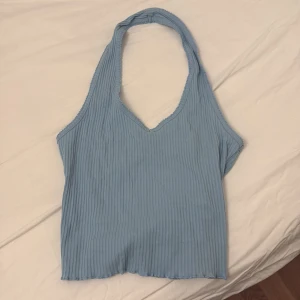 Blå ribbad halterneck-topp - Snygg blå ribbad halterneck-topp med v-ringning. Perfekt för varma dagar och ger en stilren look. Passar bra till både jeans och kjol.