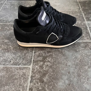 Philipe model trainers! 41 - Snygga svarta sneakers med vita detaljer och snörning. Perfekta för en stilren look. Skorna har en bekväm passform och en kontrasterande vit sula.