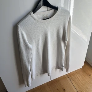 Vit stickad tröja från Jack & Jones - Säljer en stilren vit stickad tröja från Jack & Jones. Tröjan har en rund halsringning och långa ärmar, perfekt för en avslappnad look. Den är tillverkad i ett mjukt och bekvämt material. Endast en pytte liten fläck. Går 110% bort med hjälp av bikarbonat eller vanish 😇Mvh ItsForFits 