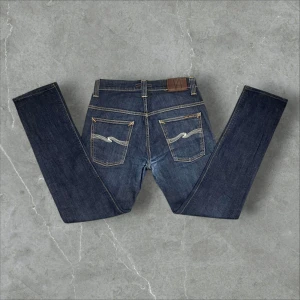 Nudie Jeans - Asfeta Nudie Thin Finns i storl 30/32 men upplevs som 28/30 (se mått.) En lagning samt förstärkningar i skrevet därav priset. Midja 36cm, ytterben 96cm och benöppning 16cm. Tveka inte att höra av dig ifall du undrar något🙂