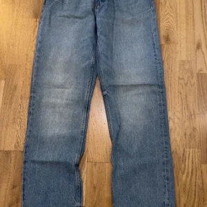 Blå jeansbyxor - Säljer ett par klassiska blå jeansbyxor med en rak passform. De har en traditionell femficksdesign och en lätt tvättad look. Perfekta för en avslappnad stil.