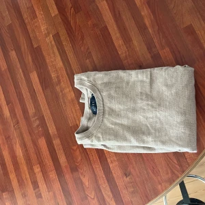 Beige tröja i merinoull från Riley - Säljer en stilren beige tröja från Riley i mjuk merinoull. Tröjan har en klassisk design med rund hals och långa ärmar, perfekt för kyligare dagar. Ett måste i garderoben för den som gillar tidlös stil. 🧥