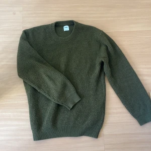 Olivgrön stickad tröja från Zara - Säljer en olivgrön stickad tröja från Zara. Tröjan har en klassisk rund hals och långa ärmar med ribbade muddar. Perfekt för kyligare dagar och ger en stilren look. Passar bra till både jeans och chinos.