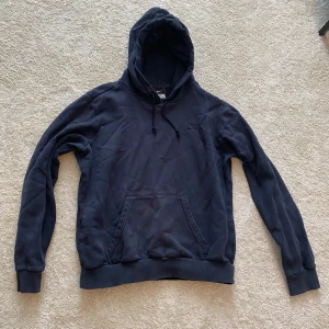 Svart hoodie från Nike - Säljer en klassisk svart hoodie från Nike med justerbar huva och känguruficka. Perfekt för en avslappnad stil. Den har långa ärmar och en liten Nike-logga på bröstet. Passar bra till både träning och vardag.
