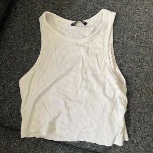 Vit ribbad linnetopp - Säljer en stilren vit ribbad linnetopp med rund halsringning. Tröjan är magtröjad.
