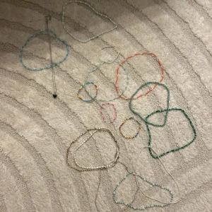 Flera olika halsband och armband och vissa är gjorda av mig för några år sedan - Säljer ett paket med flera färgglada pärlhalsband och armband, samt ett silverfärgat halsband med svart hjärthänge. Halsbanden har pärlor i vitt, blått, grönt, rosa, orange och regnbågsfärger.