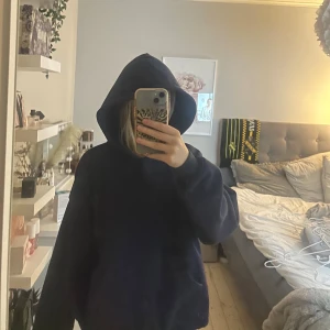 Mörkblå hoodie från Gina - Säljer en mörkblå hoodie från gina med stor huva och långa ärmar. Perfekt för dig som gillar en chill och avslappnad stil. Hoodien har en klassisk look utan tryck eller detaljer och är riktigt mjuk och skön.