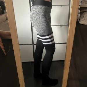 Gråsvarta leggings med vita ränder - Säljer ett par snygga träningsbyxor! De är tighta och stretchiga, perfekta för träning eller chill. Materialet är mjukt och följsamt, och designen är riktigt sportig och modern. Storlek S 🩶