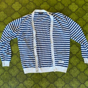 Randig kofta från Dahlin i blått och vitt - Snygg kofta från Dahlin i blåvitt randigt mönster. Långärmad med vita muddar och knäppning framtill. Size L 