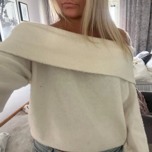Offshoulder vit stickad tröja - Superfin offshoulder stickad tröja i vitt med bred krage som vilar över axlarna. Mjuk och skön, perfekt att styla med jeans eller kjol. Långärmad och i en klassisk, enkel design som känns både trendig och chill.