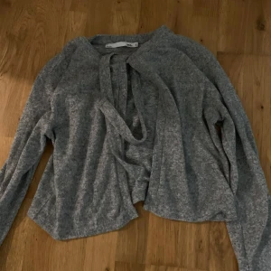 Grå kofta med knytning  - Grå kofta som man knyter vid halsen från lager 157.