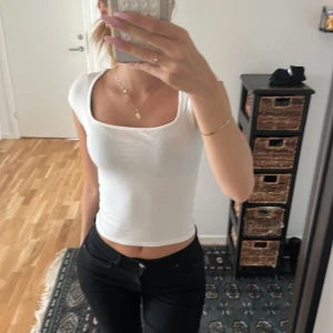 Vit croppad topp med fyrkantig ringning - Säljer en vit croppad topp med snygg fyrkantig ringning och korta ärmar. Använd max 4 gånger.