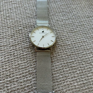 Ny Silverklocka från Hexter & Baines - Stilren klocka från Hexter & Baines med vitt ur och mesharmband i silver. Minimalistisk design med rund urtavla och tunna indexmarkeringar. Perfekt accessoar för dig som gillar en clean look och vill ha något som funkar till det mesta.oanvänd 