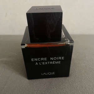 Lalique Encre Noire À L’Extrême EdP 100ml - En lyxig och mystisk parfym från Lalique, Encre Noire À L’Extrême. Flaskan är svart och fyrkantig med träinspirerat lock och tydlig logga. Doften är Eau de Parfum och rymmer 100 ml. Kommer i elegant svart kartong med orange detalj. Doften är mer för de som gillar mer ” skog” lukter. Säljer på grund av att den va för stark och tjejen tål inte det..:(  efter ett sprut luktar hela rummet, jag gillade den här verkligen men men, pris kan sänkas vid snabbaffär 