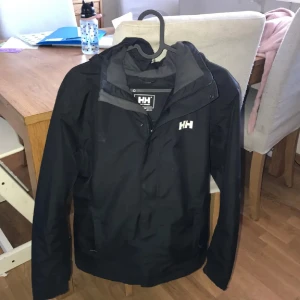 Svart Helly Hansen Jacka - En svart helly hansen jacka i storlek S. Perfekt till höst och vinter och lite kyligare dagar. Kan gå ner i pris vid snabbaffär