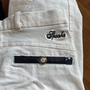 Spooks vita ridbyxor  - Säljer ett par jättefina tävlingsrisbyxor ifrån Spooks! Använda en tävling! Halvskodda med fina paljettdetaljer i marinblå. Storlek vuxen XS! Jag köpte dessa för 1500kr men har varit mitt reservpar. 