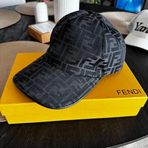 Svart Fendi keps med monogram - Snygg svart keps från Fendi med ikoniskt FF-monogram över hela kepsen. Klassisk böjd skärm och justerbar passform. Tillverkad i ett slitstarkt tyg med exklusiv känsla. Perfekt accessoar för att lyfta din outfit med lyxig streetstyle. Använd 1 gång