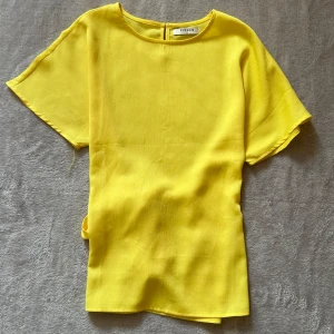 Gul blus med knyt från Pieces XS - Superfin gul blus från Pieces i storlek XS. Blusen har korta ärmar, rund halsringning och en snygg knytning i ryggen som ger en extra detalj. Perfekt för dig som vill sticka ut med färg och enkel stil. Bra skick, har några små fläckar men syns knappt❤️