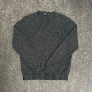 Polo Ralph Lauren tröja - Mörkgrå stickad tröja från Polo Ralph Lauren i klassisk modell med rund halsringning. Perfekt för lager-på-lager och chill stil. Priset är ej fast och hör av dig vid frågor 😉