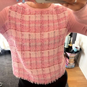 Rutig rosa kofta från Simorra - Superfin rosa kofta från Simorra med rutigt mönster i olika nyanser av rosa och ljusrosa. Koftan har långärmade ärmar, knappar bak i nacken och tweed framsida. 