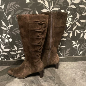 Höga klackskor  - Säljer höga klackskor i storlek 39.  Har fått skorna så inte säker men tror de är från märket ecco. Använt men i bra skick. Finns dragkedja och ”skrynkel” detalj vid benet. Köparen betalar frakten! 