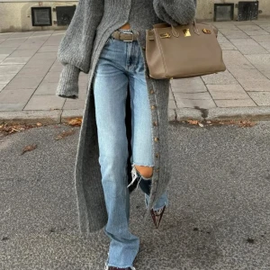 Ljusblå utsvängda jeans med hål på knät - Snygga ljusblå jeans med bootcut och mellanmidjad passform och ett hål på ena knät för en trendig, avslappnad vibe. Jeansen har klassisk femficksdesign och råa kanter nertill. Perfekta för dig som gillar en cool och laidback stil.