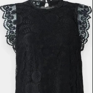 Svart spetsblus med volangärm vero mods - Supersnygg svart blus i spets med detaljerade volangärmar och hög hals. Blusen är ärmlös med vackert mönstrad spets och har en feminin, elegant look. Perfekt att styla med jeans eller kjol för en trendig outfit.