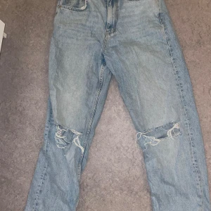 Ljusblå jeans  - Ljusblå jeans med raka ben och slitna hål över knäna från gina tricot. Klassisk femficksmodell med hög midja och snygg vintagekänsla. Perfekta för en avslappnad streetstil.
