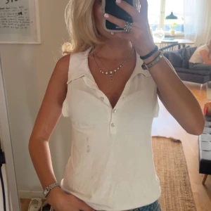 Vit topp  - Snygg vit linnetopp med klassisk krage och knappar framtill. Toppen är ärmlös och har en avslappnad passform