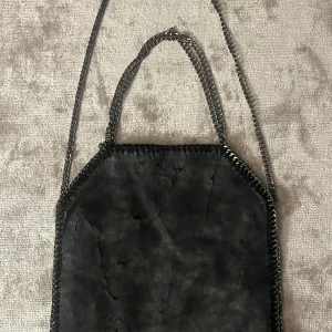 Stella mccartney väska - Cool svart axelväska med kedjehandtag och kedjerem. Väskan har en mjuk mockaliknande yta och en fyrkantig form. Kedjorna ger en edgy vibe och väskan passar perfekt till en streetstyle-look.