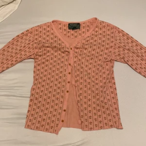 Rosa blommig kofta från Ralph Lauren - Supersöt rosa kofta från Ralph Lauren Country med små blommor i mönstret och smala ränder. Koftan har v-ringning, knappar framtill och långa ärmar. Säljer pågrund av att den är lite för liten.