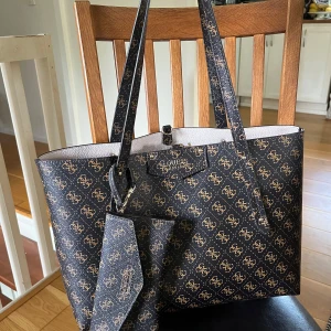 Guess Väska  - Snygg brun väska från Guess med matchande plånbok. Väskan är perfekt till skolan eller fritiden🤎🍁🍄