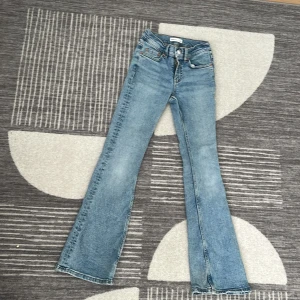 Bootcut jeans från Gina Tricot, ljusblå - Snygga ljusblå bootcut jeans från Gina Tricot, modell Perfect Jeans. Klassisk femficksdesign, hög midja och utsvängda ben. Tillverkade i mjuk bomullsdenim med en fräsch tvättad look. Perfekta för dig som gillar retrovibbar och bekväm passform.