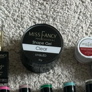 Miss Fancy Shape Gel Clear UV/LED - Miss Fancy Professional Shape Gel i färgen Clear, perfekt för att bygga och forma naglar. Gelen är genomskinlig och används med UV/LED-lampa. Kommer i en rund svart burk på 30g med skruvlock. Passar dig som vill skapa snygga naglar hemma.