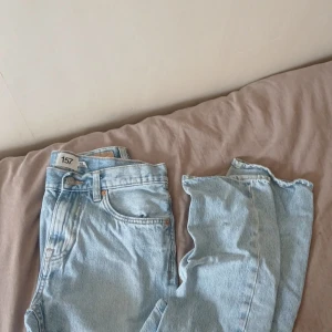 Ljusblå jeansbyxor från 157, W28 L32 - Säljer ett par ljusblå jeansbyxor från 157 med klassisk femficksdesign och raka ben. Jeansen har normal passform och är tillverkade i bomull. Perfekta för dig som gillar en enkel och stilren look.