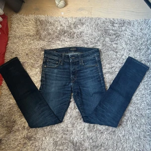 Mörkblå slim fit Jack & Jones - Snygga mörkblå slim fit  jeans från Jack & Jones med klassisk femficksdesign och läderpatch bak i midjan. Jeansen har smal passform och är tillverkade i stretchigt denim för extra komfort. Perfekta för dig som gillar en slim look.