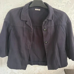 Trekvartsärm jacka från Miu Miu - Snygg mörkblå jacka från Miu Miu med klassisk krage och trekvartsärm. Orginalpris över 5000kr, använd fåtal gånger 