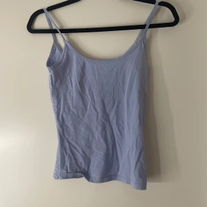 Ljusblå linne från Gina Tricot - Supersött ljuslila linne från Gina Tricot med tunna axelband och enkel, rak passform. Perfekt att styla med jeans eller kjol för en chill look. Tillverkad i mjuk bomull som känns skön mot huden.