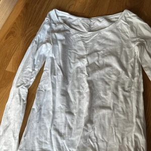 Vit långärmad topp från 157 XS - En basic vit långärmad topp från 157 i storlek XS. Tillverkad i mjuk bomull med lite stretch för en skön passform. Perfekt att styla med jeans eller kjol för en clean look. Rund halsringning och enkel design som funkar året runt.