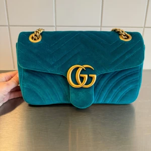 Turkos sammet axelväska från Gucci - Säljer en turkos axelväska från Gucci i lyxig sammet med guldfärgad kedja och GG-logo framtill. Dustbag, kvitto och kartong kommer med