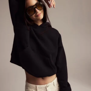 Svart Gina hoodie med huva - Svart hoodie med huva och lång ärm. Oversized passform och klassisk känguruficka framtill. Perfekt för en chill och avslappnad stil. Tjockt och mjukt material som känns skönt mot huden. 