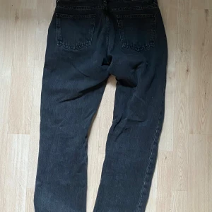 Svarta raka jeans i klassisk modell - Säljer ett par svarta jeans med raka ben och klassisk femficksmodell. Jeansen har normal passform och är tillverkade i ett robust denimtyg. Perfekta för dig som gillar en enkel och tidlös stil.