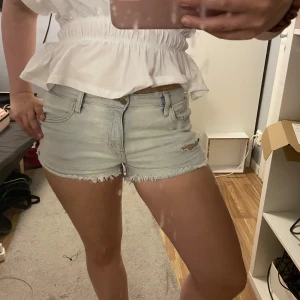 Ljusblå jeansshorts lågmidjade  - Säljer ett par ljusblå jeansshorts med lågmidjade. Shortsen har klassisk femficksmodell, låg midja och dragkedja med knapp. Perfekta för varma dagar och ger en avslappnad vibe.