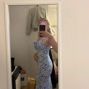 Blommig långklänning med snörning - Supersöt långklänning med blått blommönster på vit botten. Klänningen har smala axelband, figurnära passform och snörning vid bysten. Pris kan diskuteras!💗