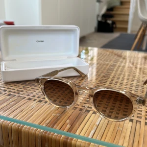 Beige runda solglasögon från CHIMI - Snygga runda solglasögon från CHIMI i modellen 03 Ecru. Bågarna är transparenta i beige ton och har bruna glas. Kommer med originalfodral. Har även boxen. Köpt på Åhléns i Malmö 2023 och är helt oanvända. Inte en repa på dom. Priset är inte hugget i sten. Hör gärna av er vid frågor eller intresse🥰🤗