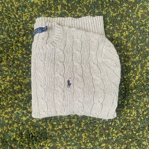 Grå kabelstickad tröja från Polo Ralph Lauren - Kabelstickad grå tröja från Polo Ralph Lauren med klassisk rund hals och broderad marinblå logga på bröstet. Tröjan är långärmad och har ribbade muddar och nederkant. Perfekt för lager-på-lager och snygg till jeans eller chinos. Nypris 2400 kr Mitt pris 649 kr 💯 Priset går självklart att förhandla ner vid snabb köp!
