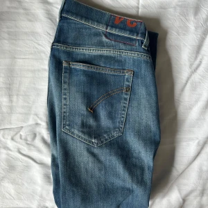 Dondup Jeans Blå - Snygga Dondup jeans i storlek 34 men sitter som 32-33 jeansen är i modell Ritchie som sitter slim/skinny precis som den mest populära modellen George. Byxorna har slim passform med kontrastsömmar och en liten logga bak i midjan. Perfekta för en avslappnad och stilren look.